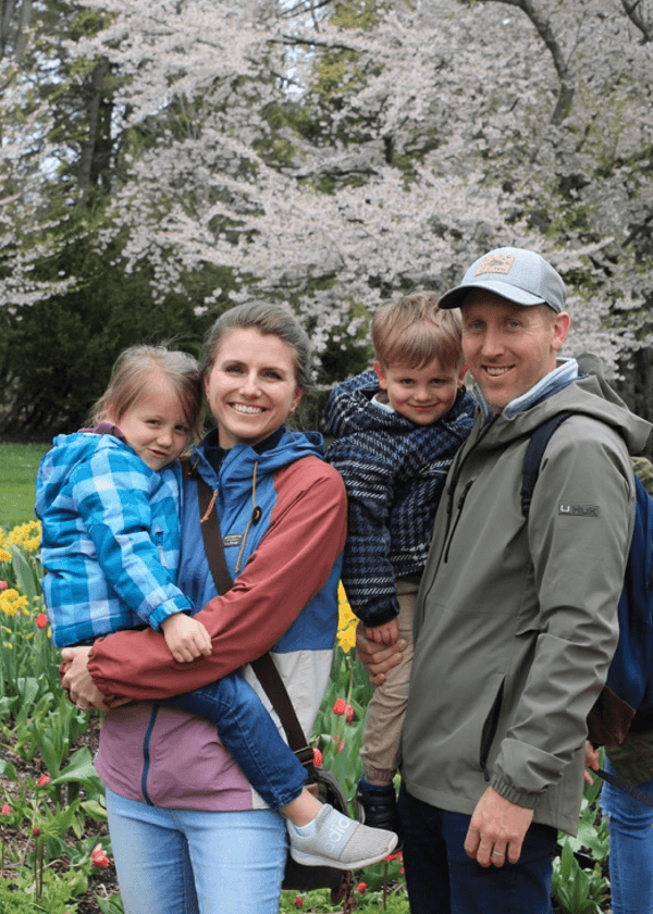 Molly's immediate family posing in front of flowering trees and plants.